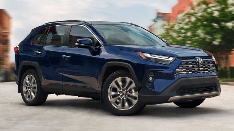 2025 Toyota RAV4 cornering on a paved surface with buildings in the background