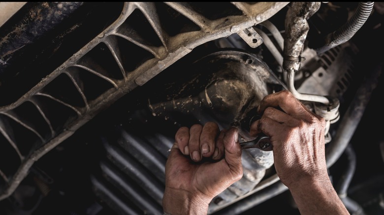 A mechanic's hands torquing a bolt in a tight spot.