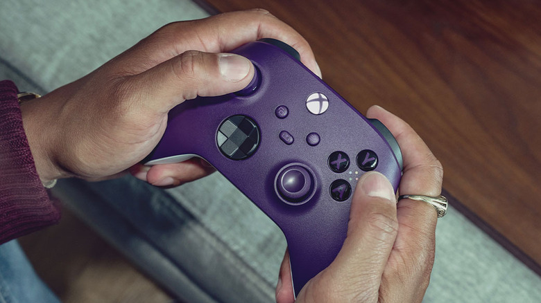 A purple wireless Xbox One controller being held by two hands.