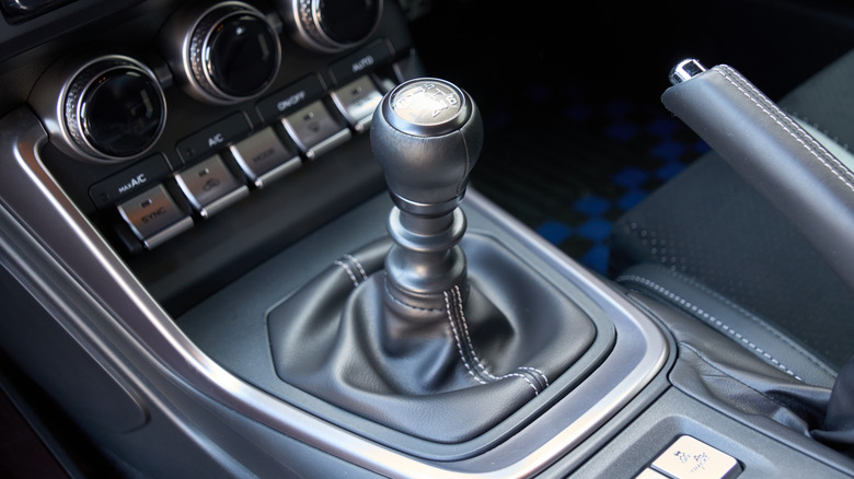 High-angle view of the manual transmission car shift lever, handbrake, and other control buttons and dials