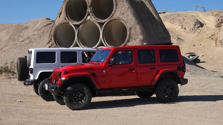 Two Jeep Wrangler parked near a sandy hill