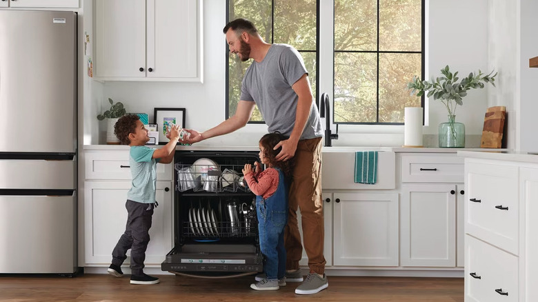 Man taking dishes out of Frigidaire dishwasher and handing glass to child