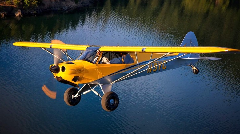 Yellow Carbon Cub flying over lake