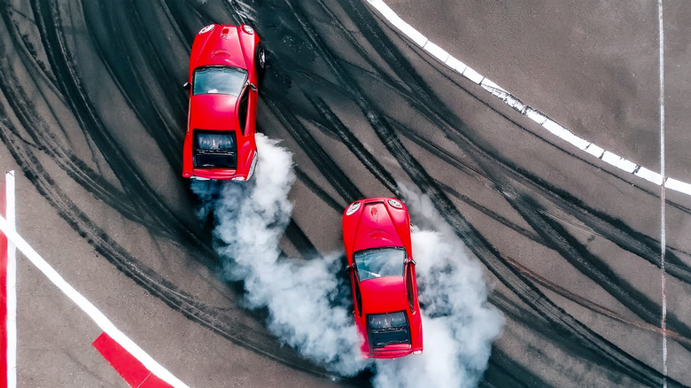A top down view of two cars drifting on a track.
