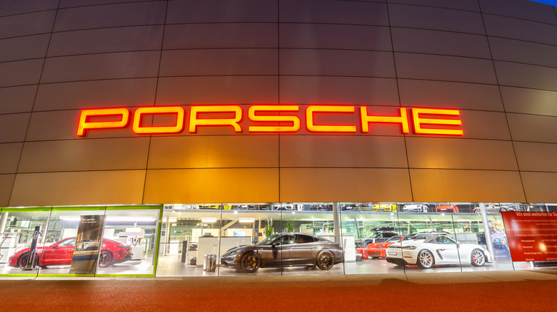 A Porsche dealership at night, with several models on display in the windows
