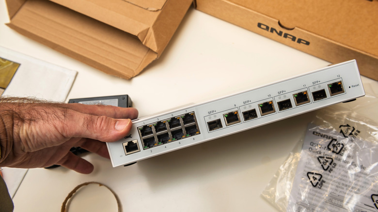 A 10 Gigabit Ethernet Router being held among packaging, with the ports visible.