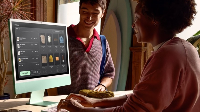 Woman using iMac alongside man