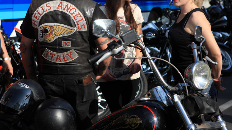 A Hells Angels member standing with other behind a motorcycle during the 2010 Harley Davidson gathering