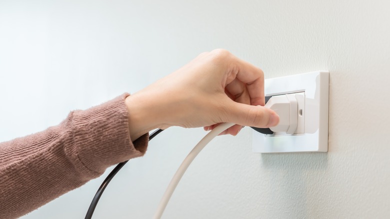 Woman plugging into wall outlet
