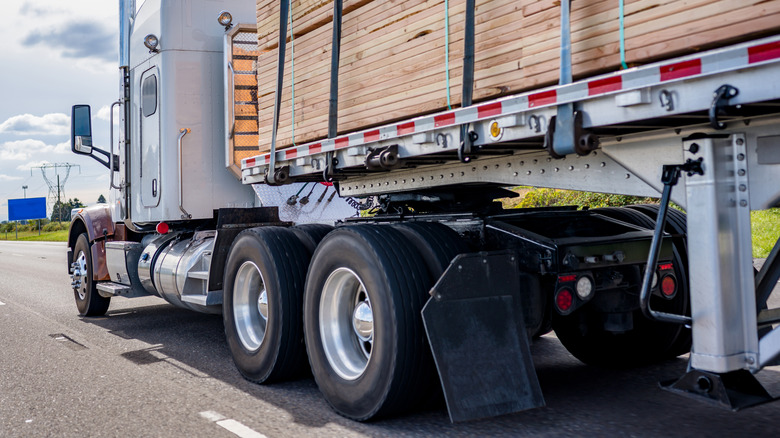 A semi-truck with mud flaps driving on a paved road