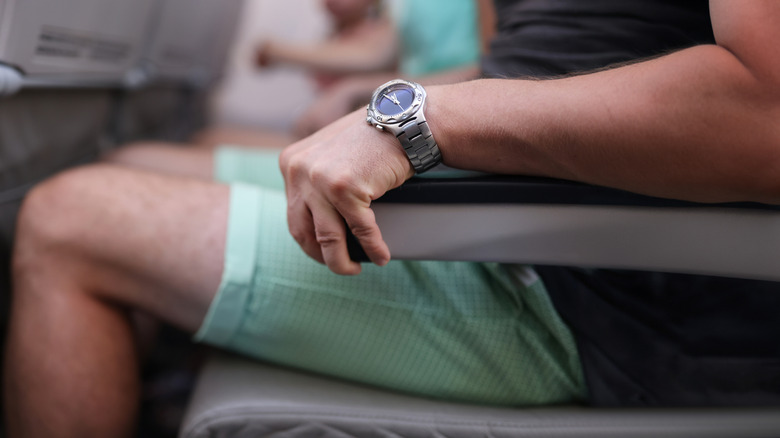 Person holding armrest of aircraft.