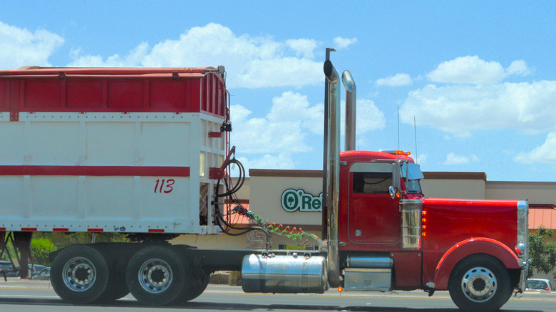 A red Peterbilt 379 6x4 truck and tractor trailer driving on a city street on a sunny day