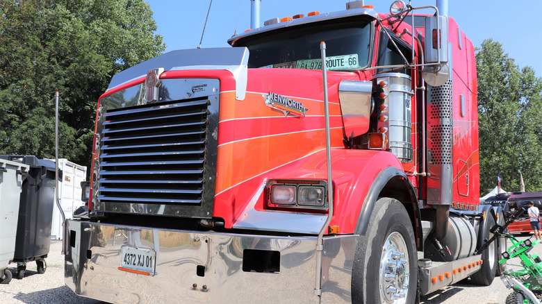 A red traditional style heavy-duty Kenworth W900 truck parked on a sunny day