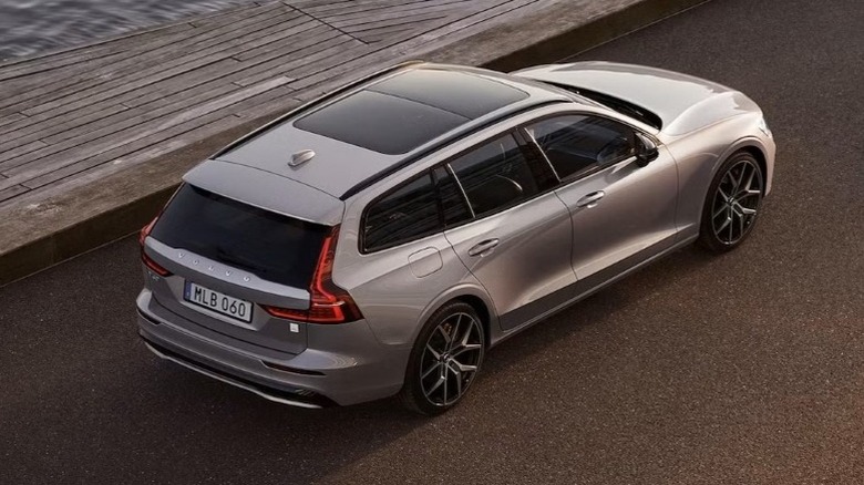 Silver V60 Polestar Engineered plug-in hybrid wagon parked on an asphalt surface near a body of water