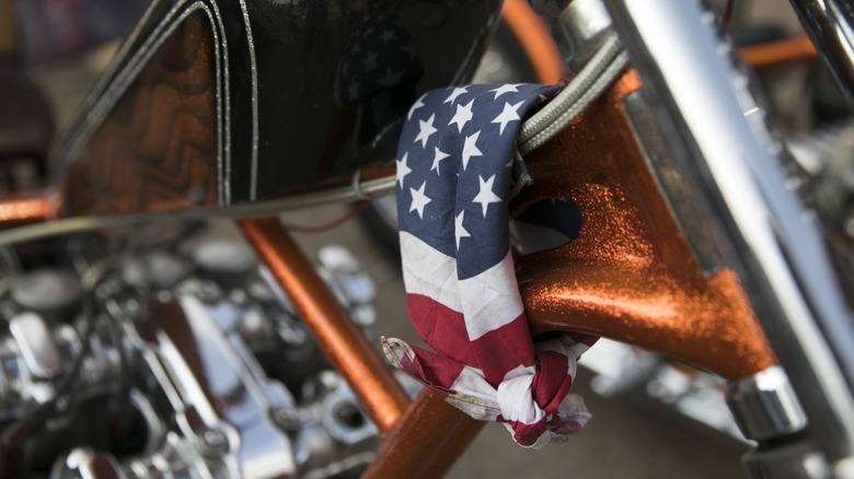 A red, white, and blue bandana tied to a motorcycle frame near the forks.