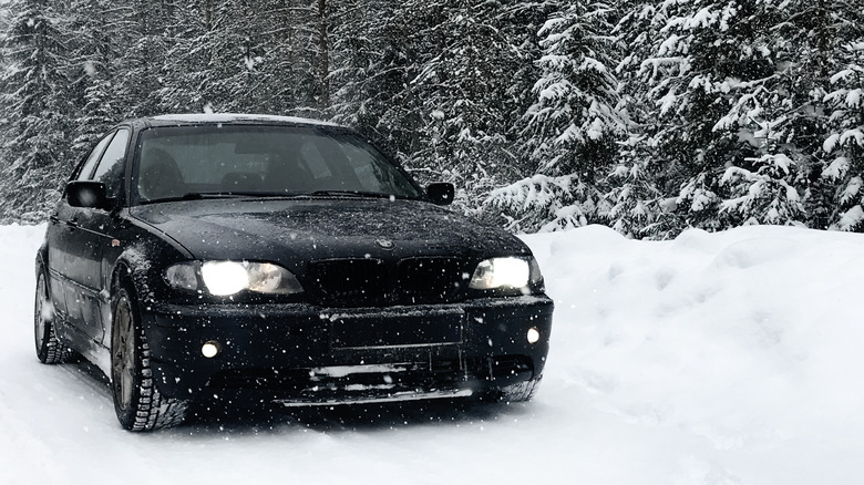 A BMW 3 series driving in a snowy forest
