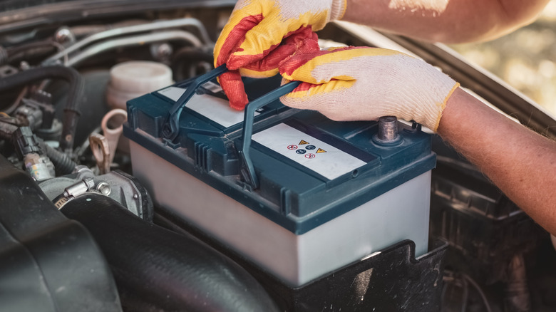A mechanic fits a battery with a small vent hole visible