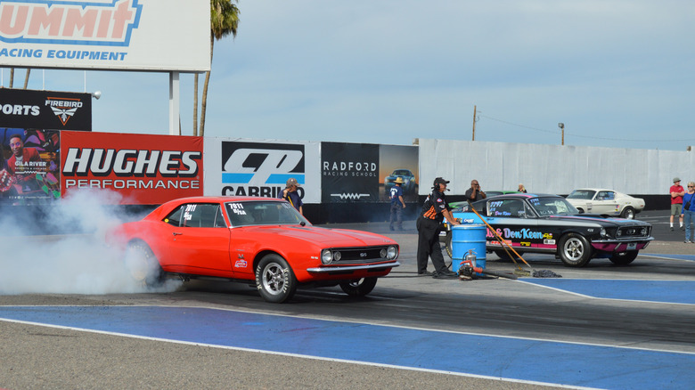 Red 1967 Chevrolet Camaro doing burnout on drag strip
