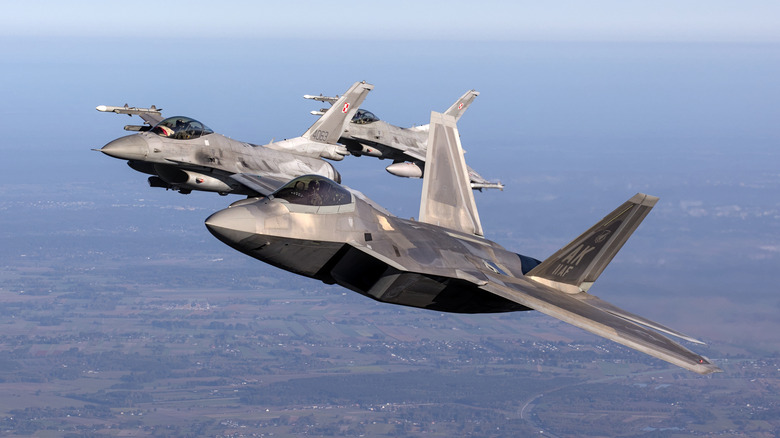 US Air Force F-22 RAPTOR fighter jets flying in formation with F-16s
