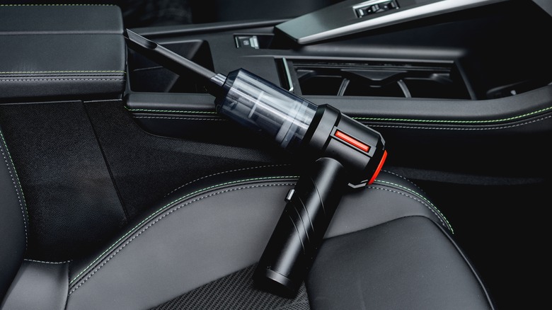 Close-up shot of a car front seat with handheld vacuum cleaner resting on it