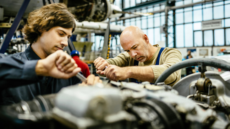Two male aircraft mechanics working on an aircraft engine