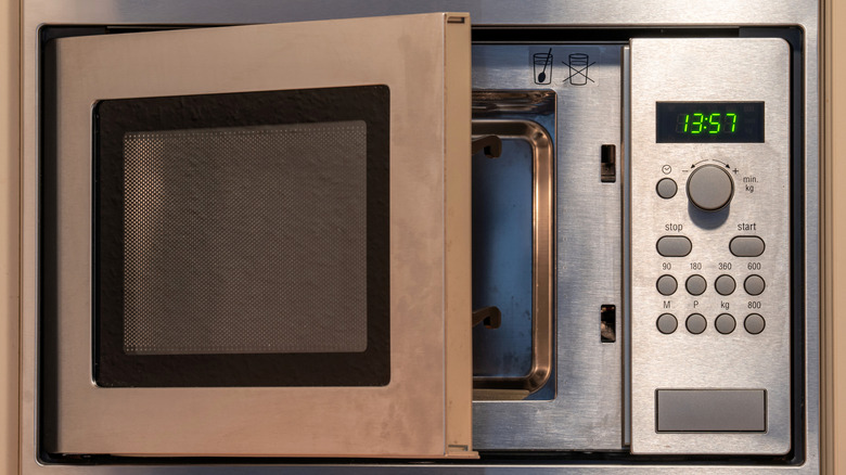 A stainless steel microwave with door ajar showing mesh layer