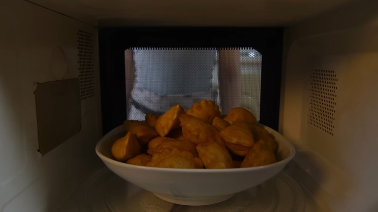 A view from inside a microwave showing food cooking behind mesh layer over the door