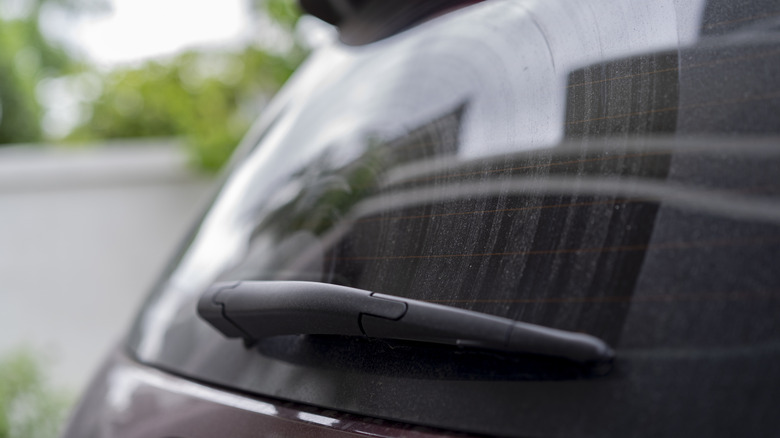 A rear window wiper on a slightly dusty rear window, off position