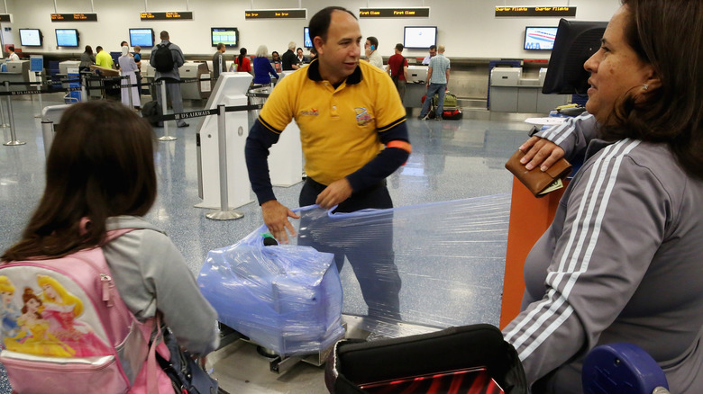 A person wrapping their luggage at the airport.