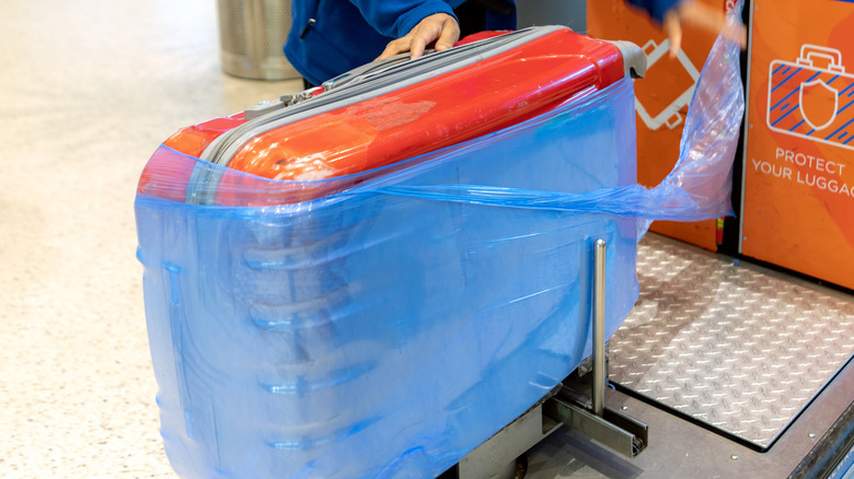 A person wrapping their luggage at the airport.
