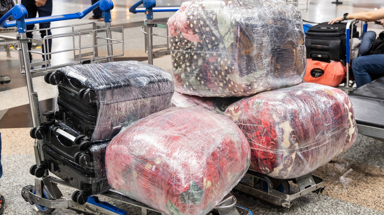Wrapped luggage in an airport on carts.