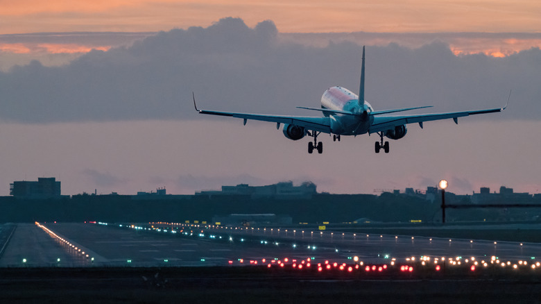 Plane landing on a runway at sunrise