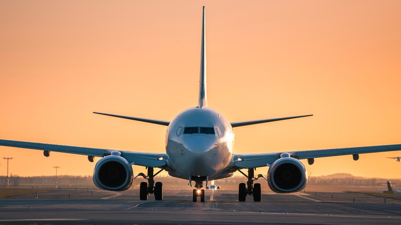 Front view of plane on runway against goldensunset