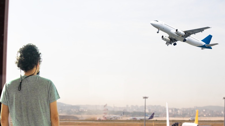 Person watching plane take off from window
