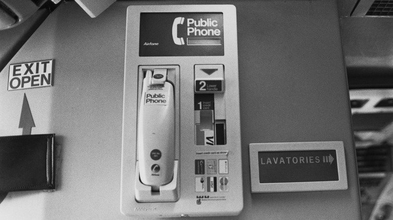 An Airfone public phone and a sign to the lavatories on board a passenger plane