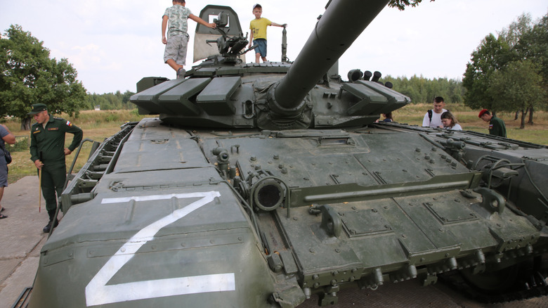 Children play on a Russian tank painted with the letter Z during a military event outside of Moscow