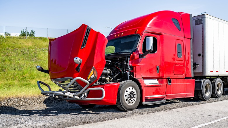 Red semi-truck parked with hood up