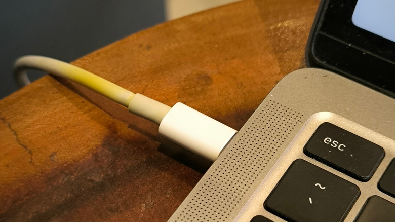 A yellowing charging cable connected to a MacBook.