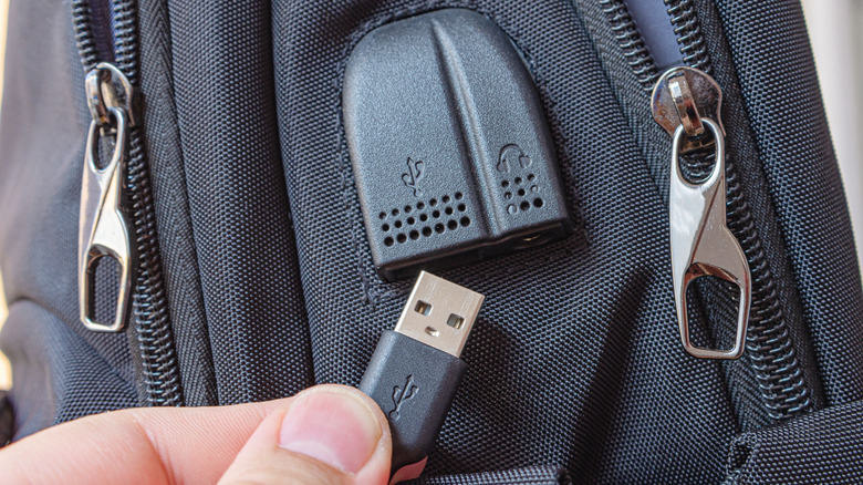 Connecting a charging cable to USB port on black backpack