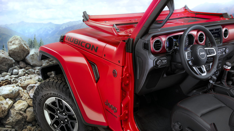 2018 Jeep Wrangler on rocky surface with doors removed and windshield folded down, close-up view beside left-hand side