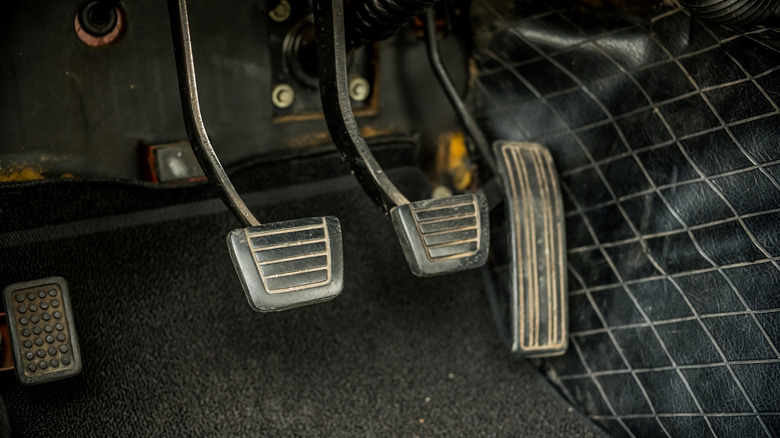 Pedals inside a vintage car - left to right -- parking brake pedal, clutch pedal, brake pedal, gas pedal.