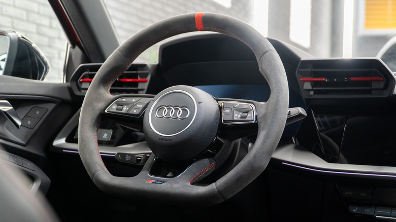 An Audi RS3 flat bottom steering wheel wrapped in Alcantara with red stitching.