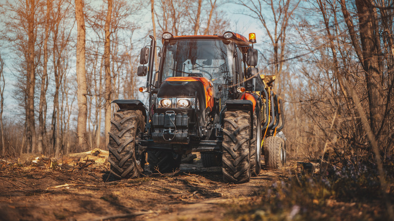 An orange tractor on a muddy trail, front view