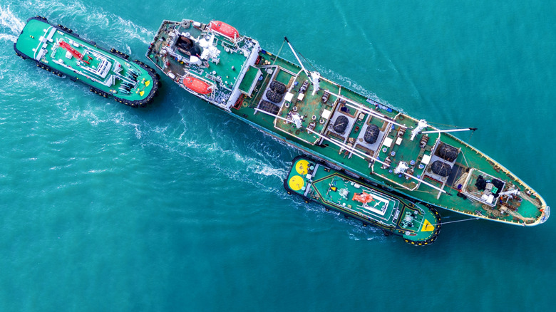 tugboats guiding large ship in water