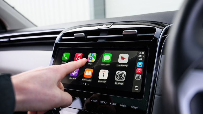 A person using Apple CarPlay on a car's infotainment screen.