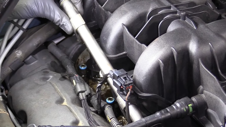 A person removing their fuel rail to inspect the fuel injectors.