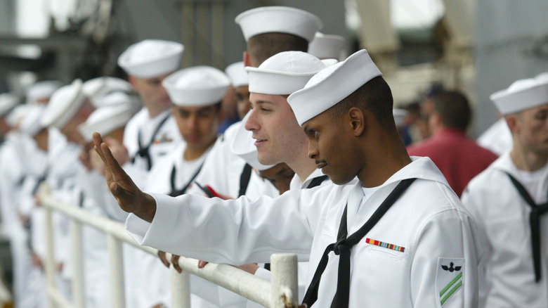 A group of sailors look out from the ship while performing 