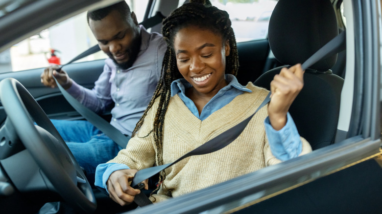 Two people fastening vehicle seat belts