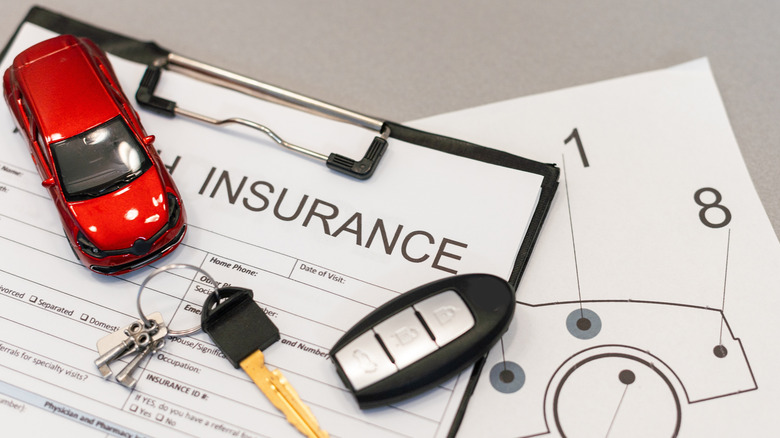 Keys on top of car insurance paperwork.