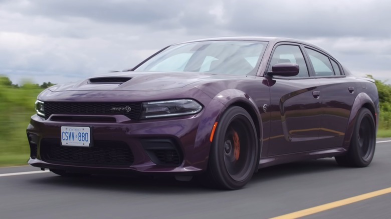 A purple Dodge Charger Hellcat driving on a road